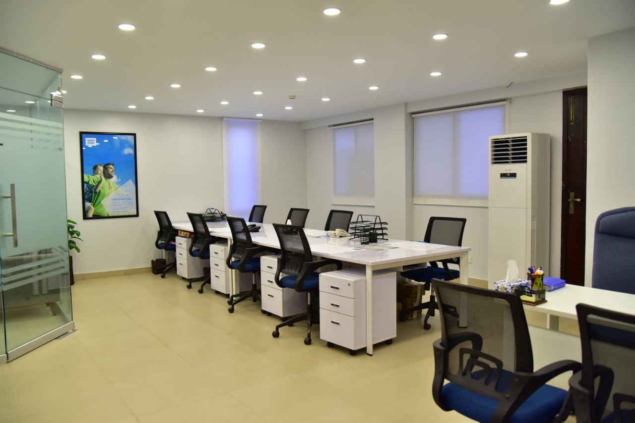 Row of open-plan desks beneath recessed lighting