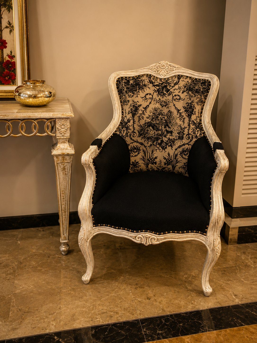 Cream wingback chair with black floral upholstery against marble console