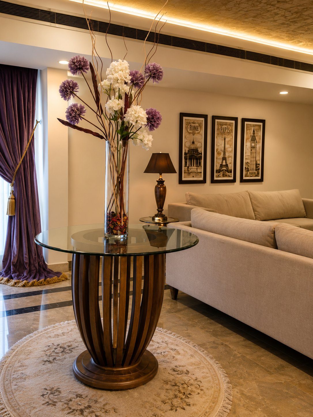Glass side table with travel-themed framed prints and cream sofa